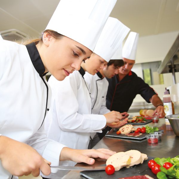 Team of young chefs preparing delicatessen dishes